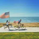 man riding bike and woman running holding flag of USA