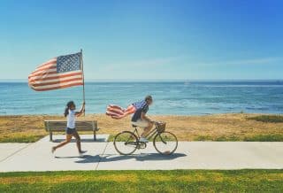 man riding bike and woman running holding flag of USA