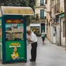 man in white dress shirt and black pants standing beside blue and yellow food stall