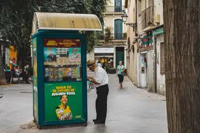 man in white dress shirt and black pants standing beside blue and yellow food stall